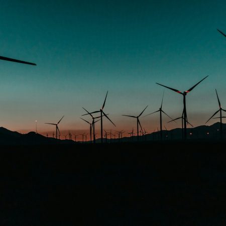 chartis-energy-50-trade-surveillance Rows of wind turbines on a hill at sunset