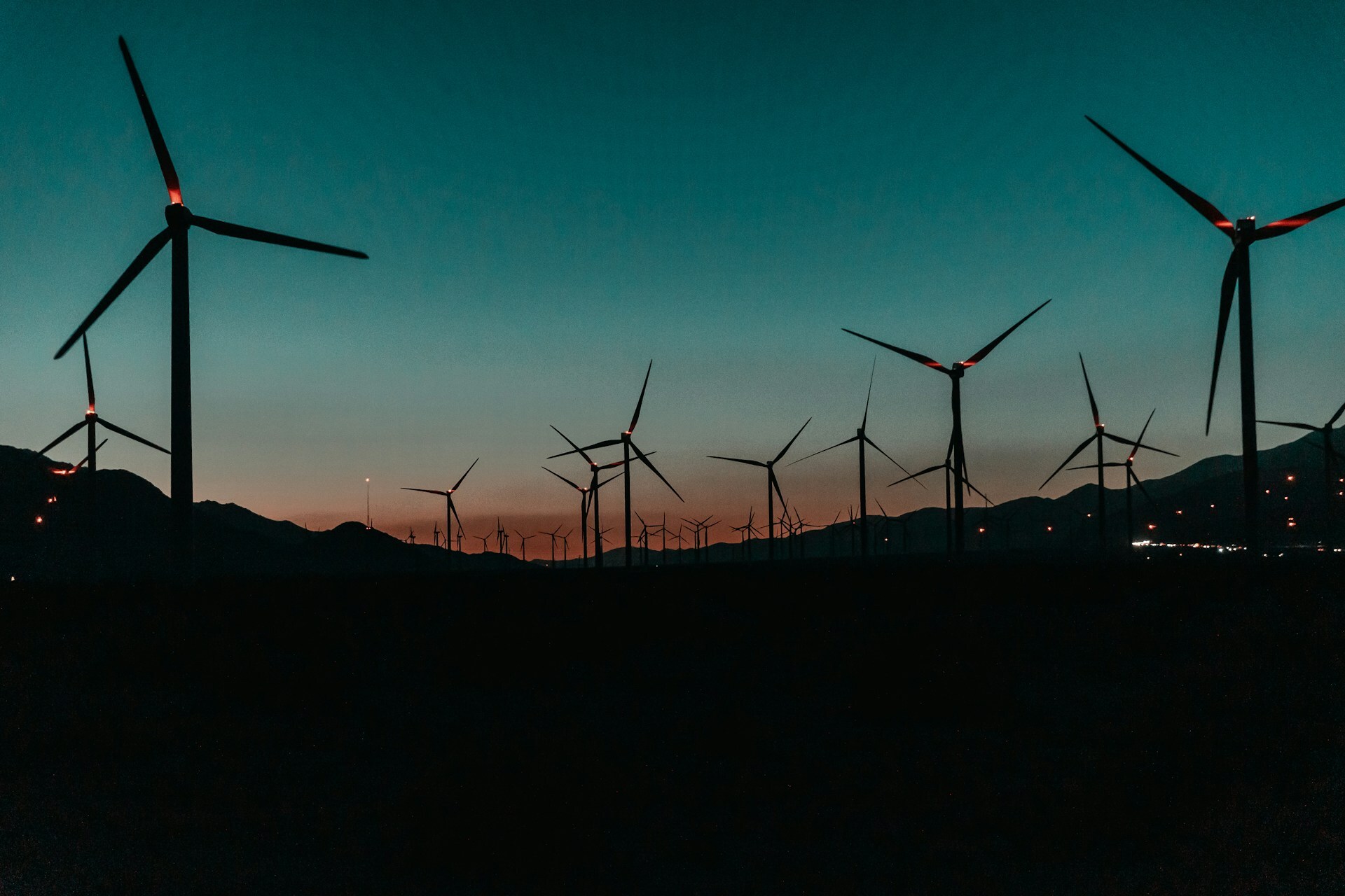 Rows of wind turbines on a hill at sunset
