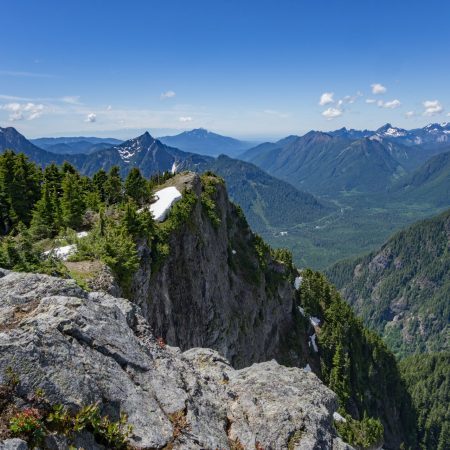 Solutions banner A series of mountain ranges covered in green trees with blue skies and soft clouds