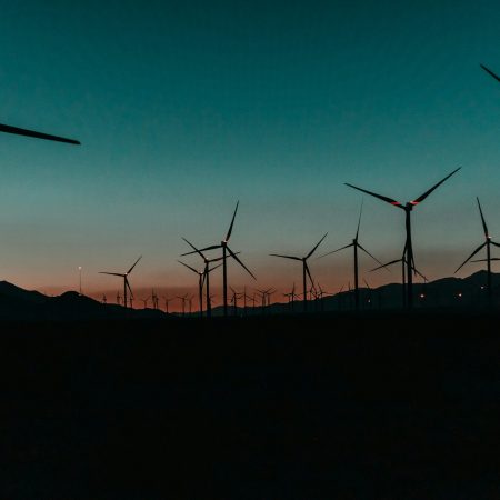 Rows of wind turbines on a hill at sunset