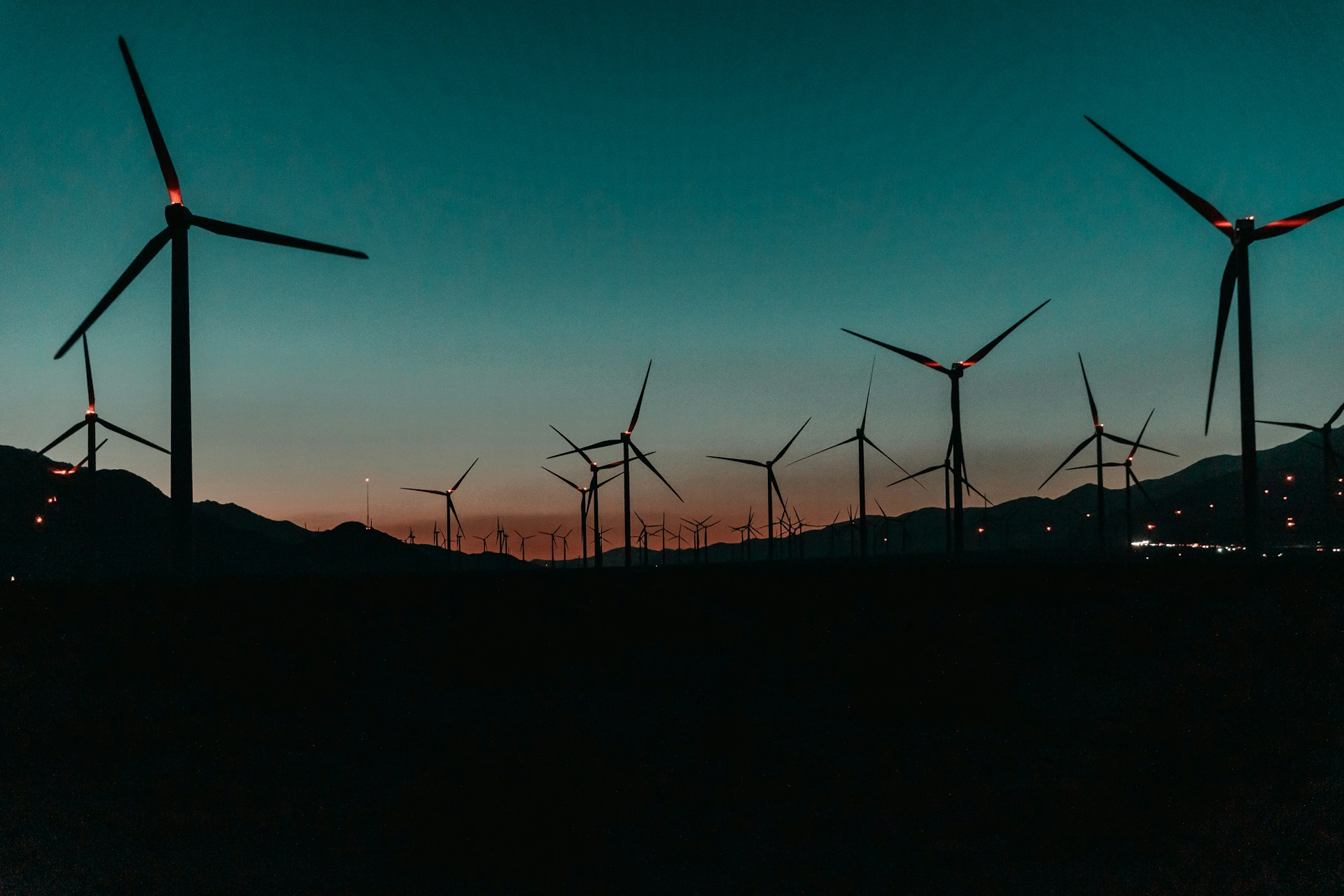 Rows of wind turbines on a hill at sunset
