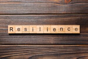 scrabble pieces on wood table spelling out the word resilience