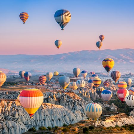Aerial view of a fleet of hot air balloons, in Cappadocia, Turkey, at sunrise. Cappadocia is a popular tourist destination.