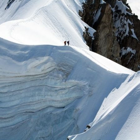 two people standing on the edge of a mountain ridge